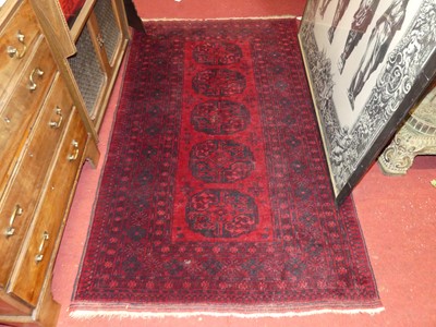 Lot 1136 - A Persian woollen red ground bokara rug,...