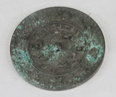 Lot 138 - A Chinese cast metal mirror, relief decorated...