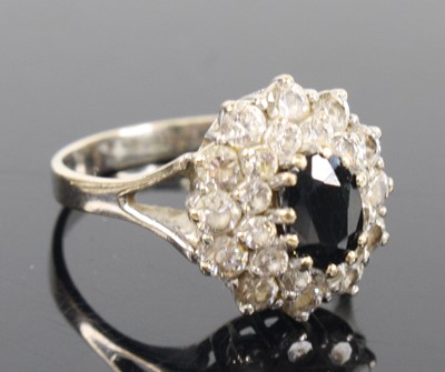 Lot 1303 - A white metal sapphire oval cluster ring,...