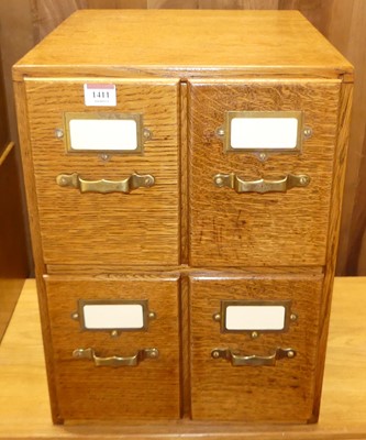 Lot 1411 - A 1930s oak table-top bank of four index...