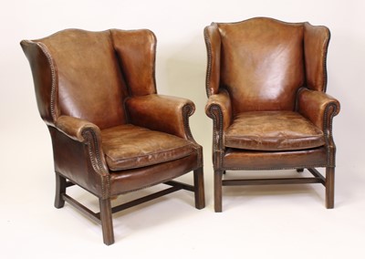 Lot 1554 - A pair of tan leather wing armchairs in the...