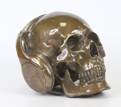 Lot 45 - A bronzed model of a skull wearing headphones,...
