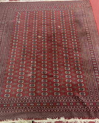 Lot 1156 - A Persian woollen red ground Bokhara rug,...