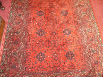 Lot 1197 - An Afghan style red ground woollen rug,...