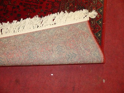 Lot 1197 - An Afghan style red ground woollen rug,...