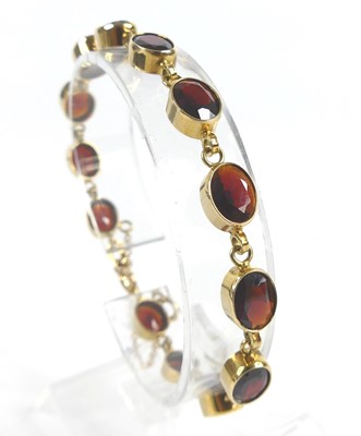 Lot 2634 - A 9ct yellow gold garnet bracelet, comprising...