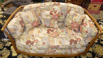 Lot 1383 - An Ercol mid-elm two-seater sofa, having...