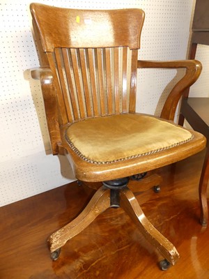 Lot 1159 - A 1930s oak tub slat back swivel desk elbow...