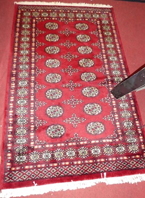 Lot 1187 - A Persian woollen red ground Bokhara hall rug,...