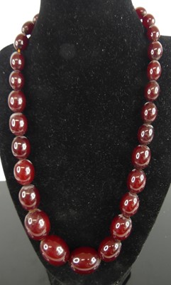 Lot 438 - A beaded cherry amber necklace, arranged as 31...