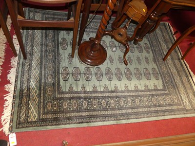 Lot 1163 - A Persian woollen green ground Bokhara rug,...