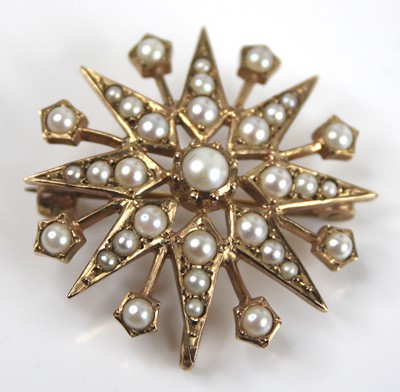 Lot 2684 - A 9ct yellow gold pearl set 16-ray star brooch,...