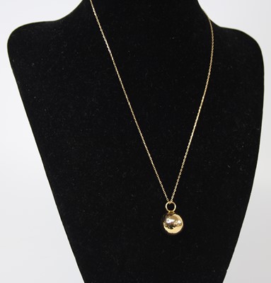 Lot 2497 - A modern 14ct gold ball pendant, dia.15mm, on...