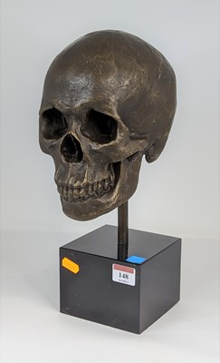 Lot 148 - A bronzed metal model of a skull, mounted upon...