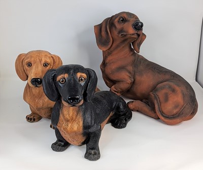 Lot 204 - Three modern resin models of dachshunds,...