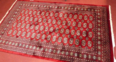 Lot 1176 - A Persian woollen red ground Bokhara rug, 242...