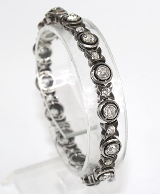 Lot 2327 - A white metal diamond line bracelet, featuring...