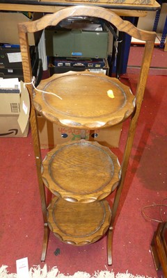 Lot 1409 - An oak circular three-tier folding cake stand