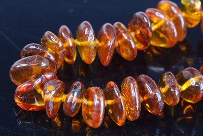 Lot 333 - A clear orange amber single knotted string...