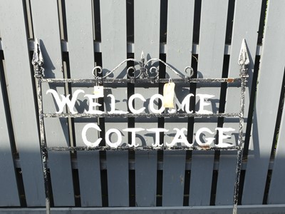 Lot 1442 - A painted wrought iron sign 'Welcome Cottage',...