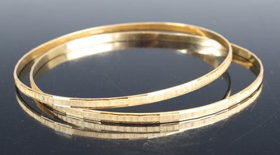 Lot 2590 - A pair of modern 18ct gold bangles, each with...