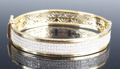 Lot 2591 - A modern 14ct gold cz set hinged bangle, one...