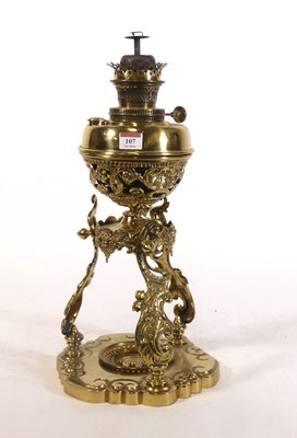 Lot 107 - A brass oil lamp, on scrolled foliate supports...