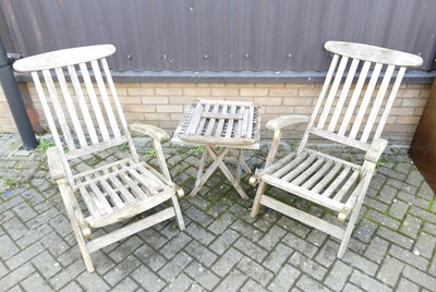 Lot 1407 - A pair of slatted teak folding garden steamer...