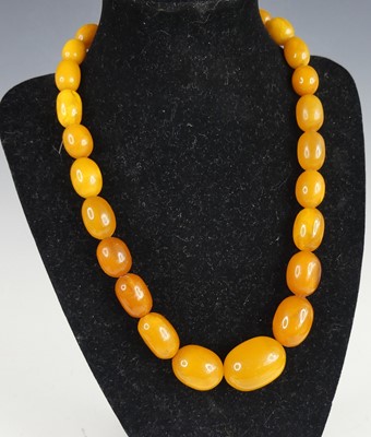 Lot 2602 - A beaded butterscotch amber necklace, arranged...