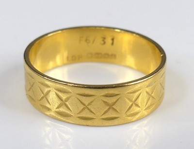 Lot 2762 - A modern 22ct gold wedding band, with carved...