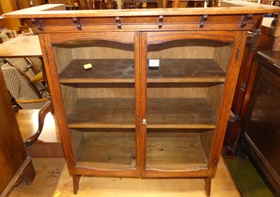 Lot 1257 - An Arts & Crafts oak double door glazed table...