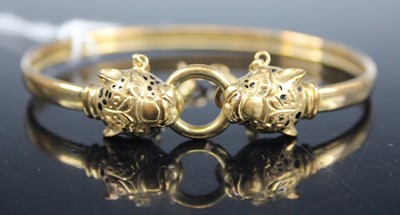 Lot 430 - A yellow metal bangle, each end fashioned as...