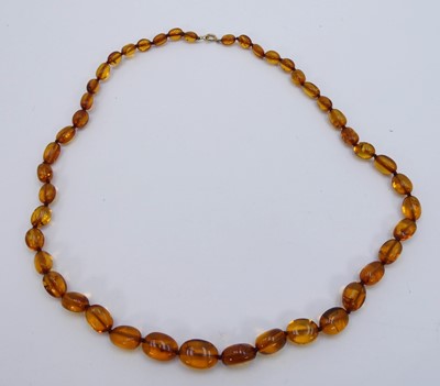 Lot 313 - A beaded clear orange amber necklace, having a...