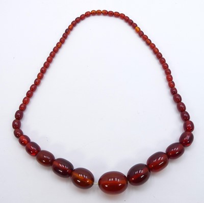 Lot 319 - A faux amber beaded necklace, arranged as...