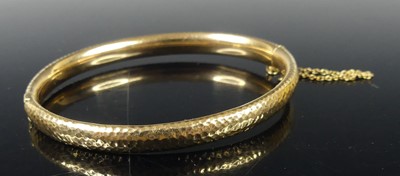 Lot 2286 - A 15ct gold hinged bangle, with textured...