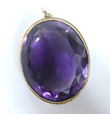 Lot 2583 - A yellow metal oval amethyst pendant, the...