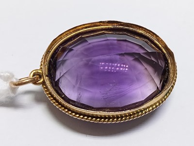 Lot 2583 - A yellow metal oval amethyst pendant, the...
