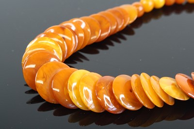 Lot 384 - An orange amber necklace, arranged as polished...