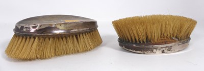 Lot 384 - A pair of George V silver-clad clothes brushes