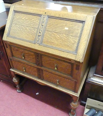 Lot 1397 - A 1930s moulded oak slopefront two drawer...