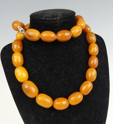 Lot 2243 - A butterscotch amber barrel bead necklace,...