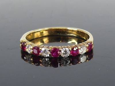 Lot 2642 - A yellow metal, ruby and diamond half eternity...