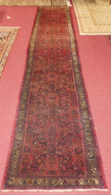 Lot 1139 - A Persian woollen red ground Tabriz long hall...