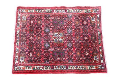 Lot 1142 - A red ground Persian rug, the red ground with...
