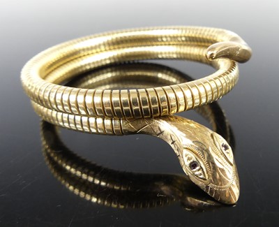 Lot 2829 - A modern 9ct gold snake bangle, the carved...