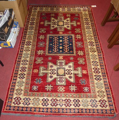 Lot 1169 - A red, blue and cream ground Kazak rug, with...