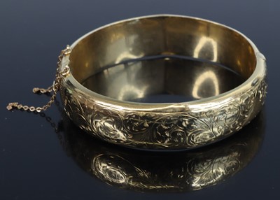 Lot 374 - A 9ct gold and engraved hinged bangle with...