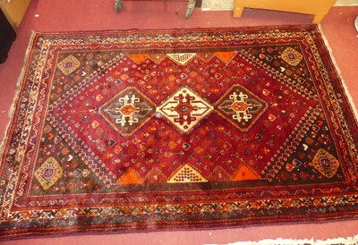 Lot 1244 - A Persian woollen red ground Shiraz rug, with...