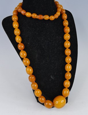 Lot 2587 - A butterscotch amber beaded necklace, arranged...